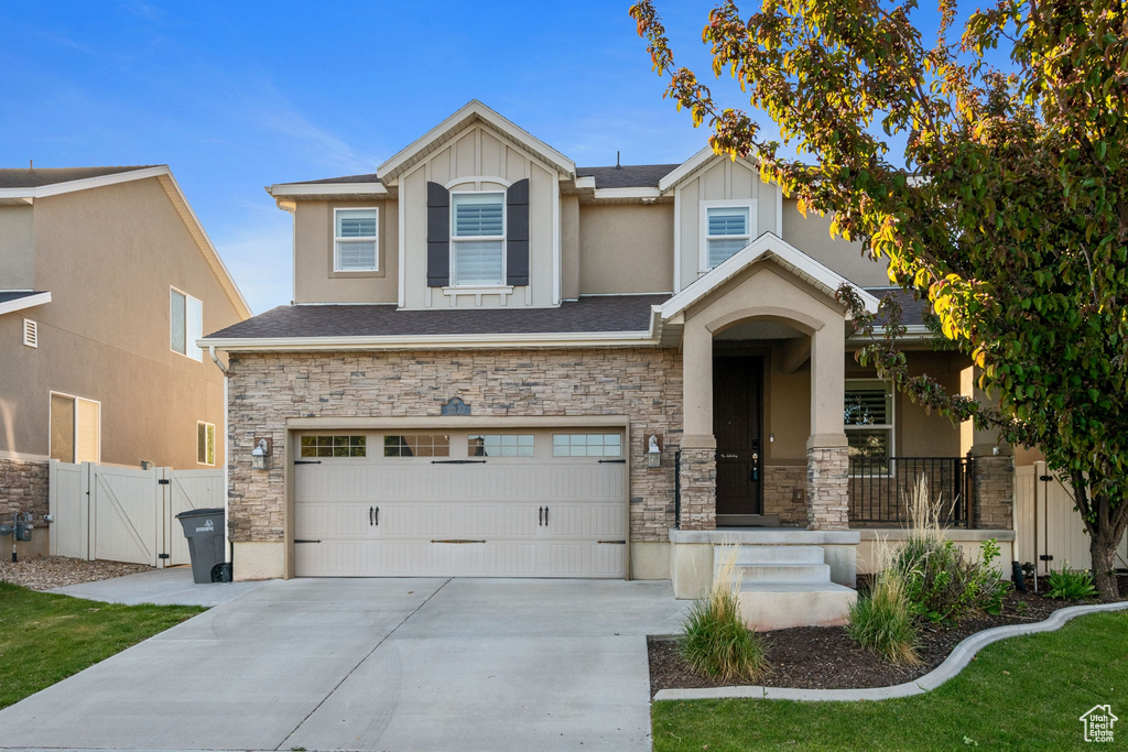 View of front of property with concrete driveway, a garage, a gate, and stone siding