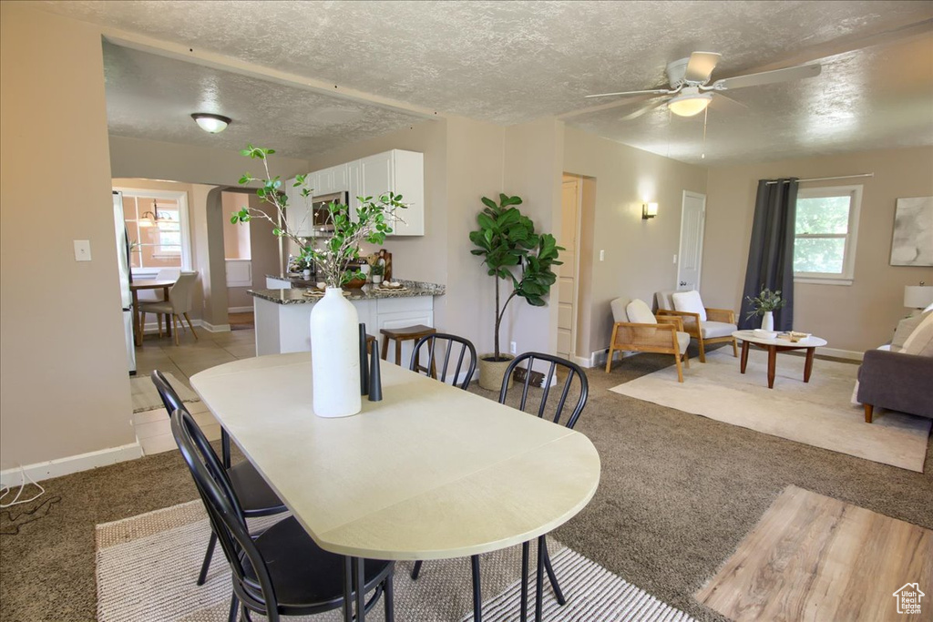 Carpeted dining space with a textured ceiling, baseboards, and a ceiling fan