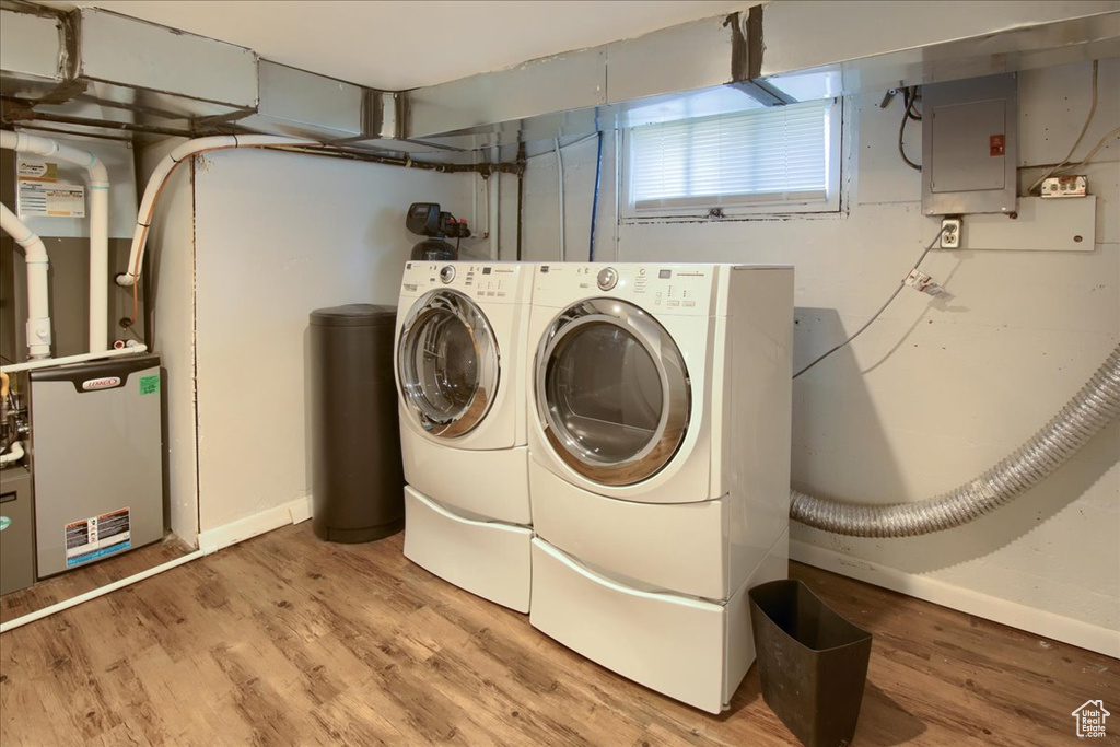 Washroom with electric panel, independent washer and dryer, light wood finished floors, and baseboards