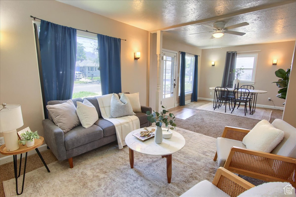 Living area featuring light carpet, ceiling fan, and baseboards