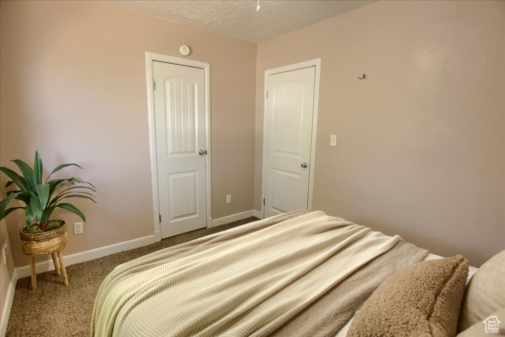 Bedroom with carpet, baseboards, and a textured ceiling