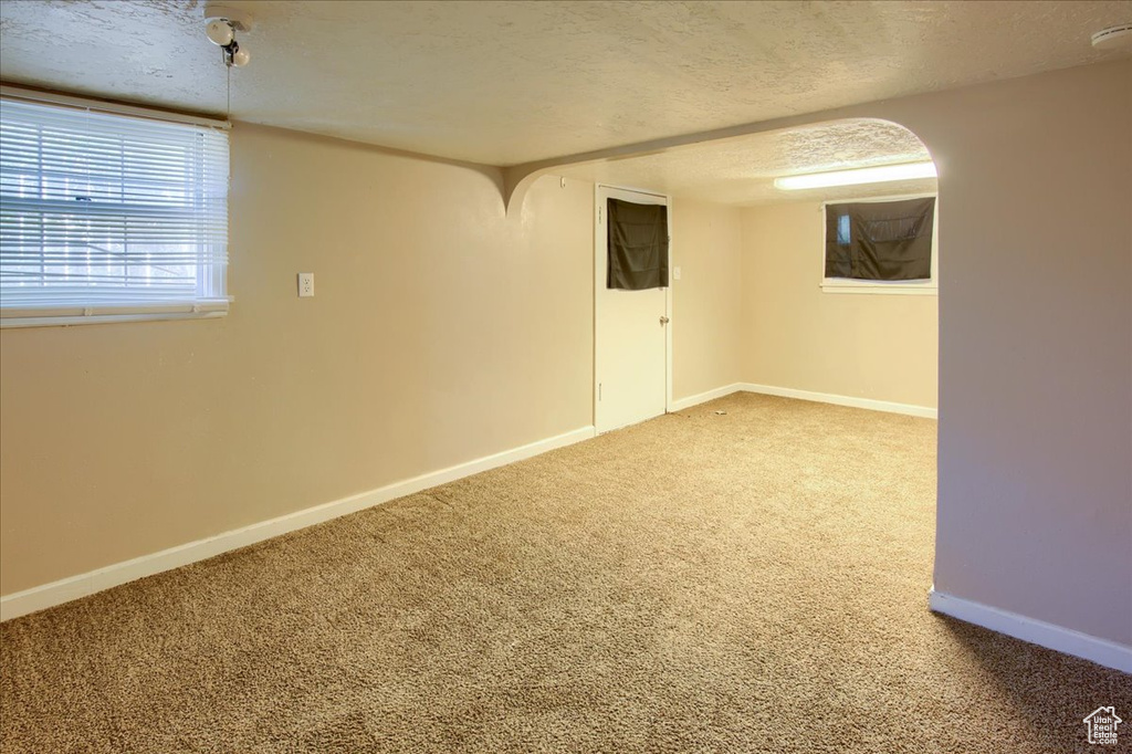 Below grade area featuring carpet floors, baseboards, and a textured ceiling