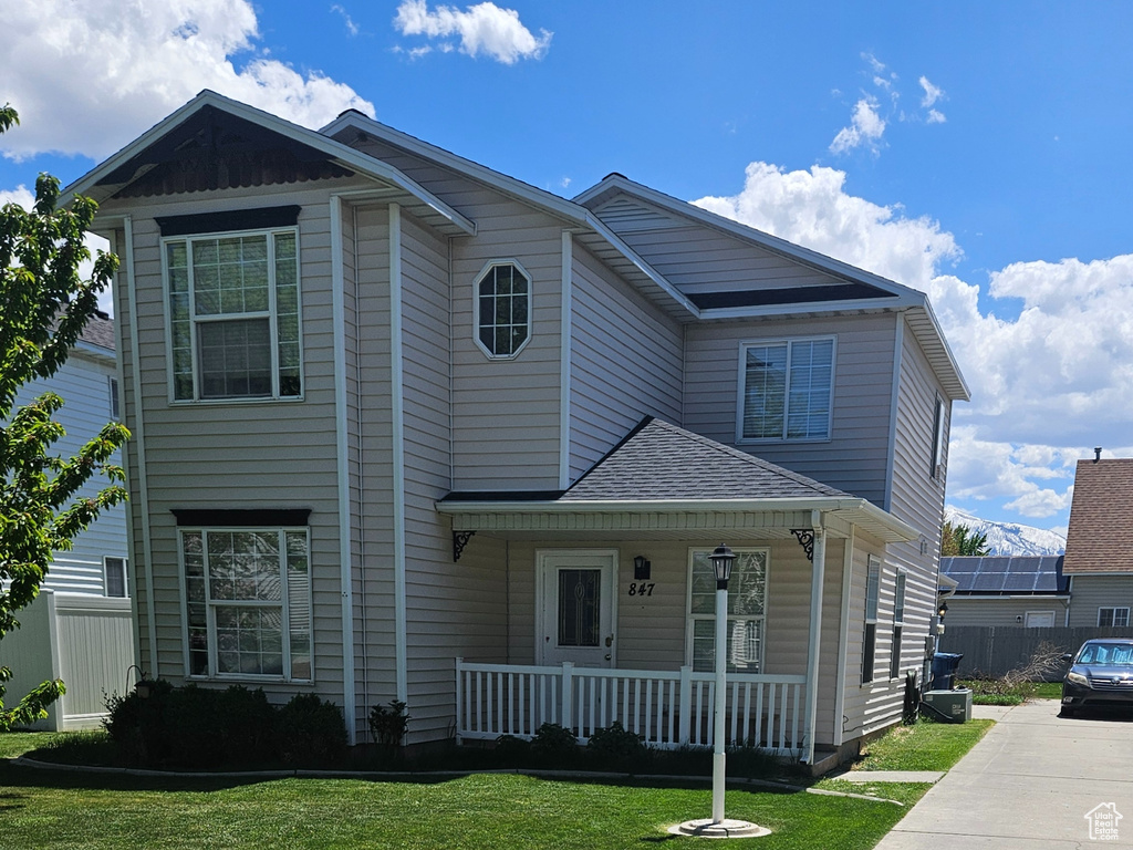 View of front of home featuring a porch, fence, a front lawn, and concrete driveway