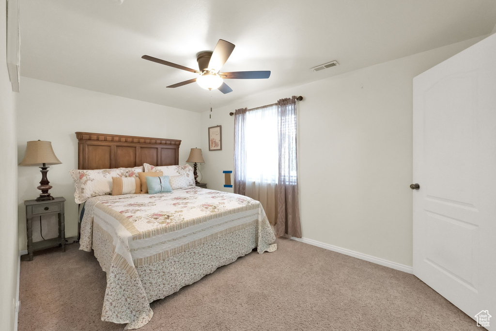 Bedroom with baseboards, visible vents, light carpet, and ceiling fan