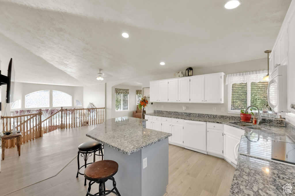Kitchen featuring plenty of natural light, light stone countertops, a kitchen island, and white appliances