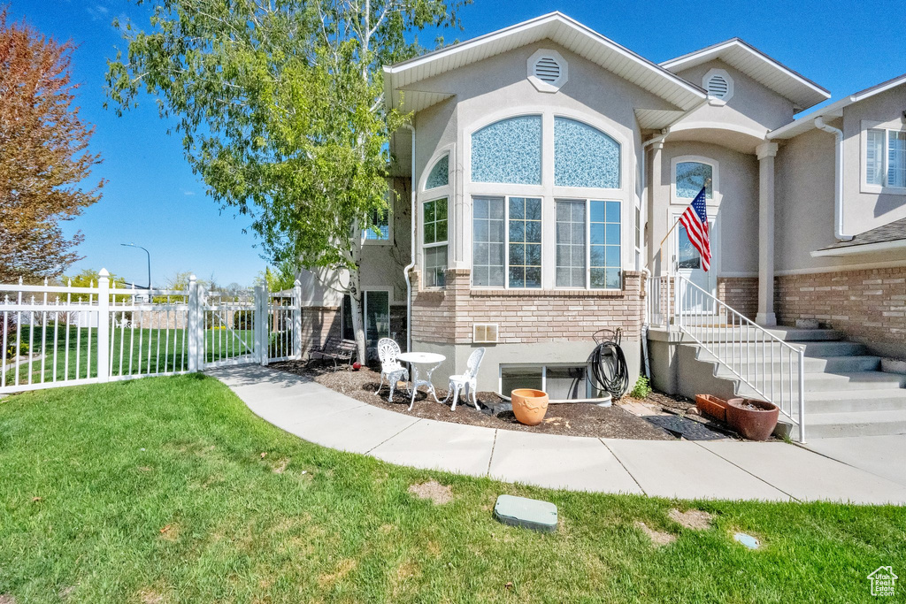 View of front of home featuring brick siding, fence, stucco siding, and a front yard