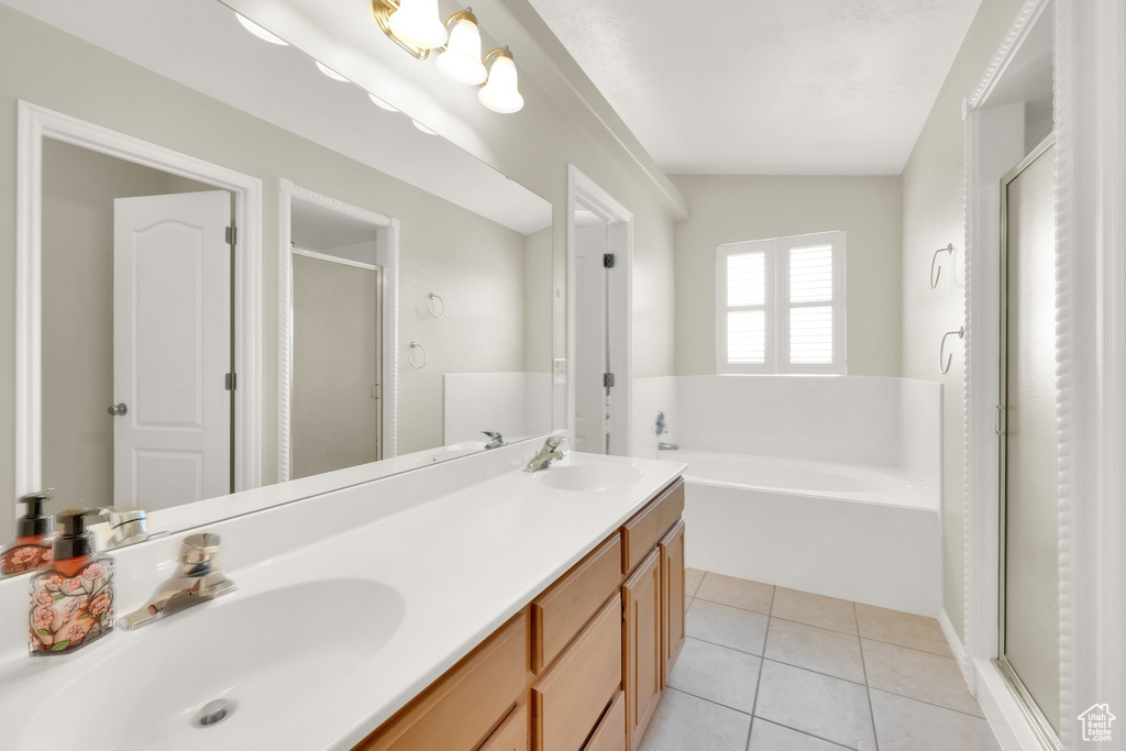 Bathroom featuring double vanity, a bath, a stall shower, and a sink
