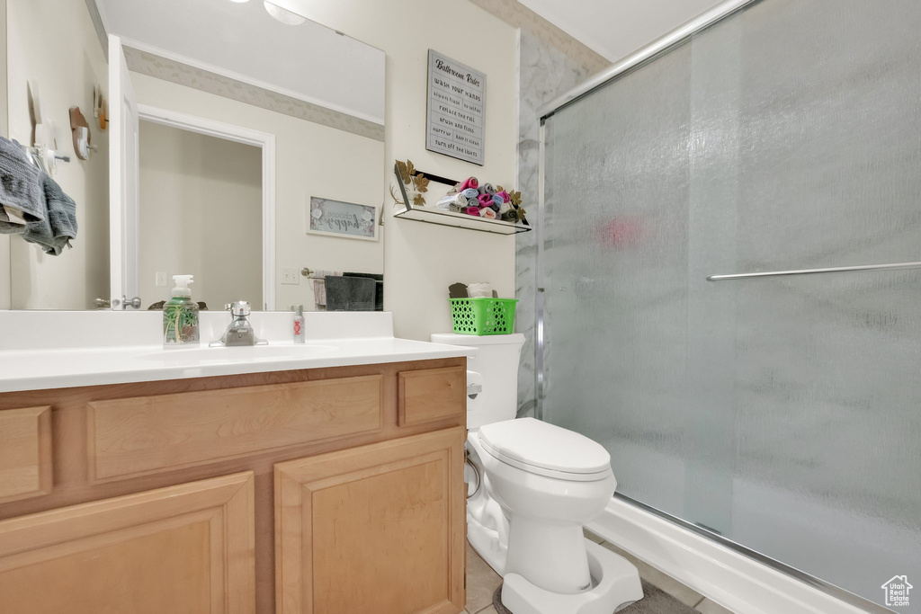 Bathroom featuring vanity, toilet, tile patterned flooring, and a stall shower