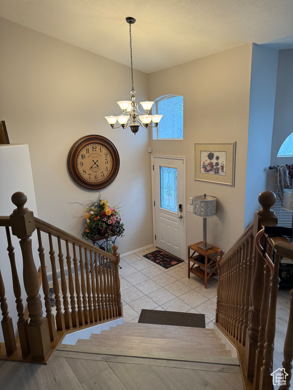 Entryway featuring baseboards, light tile patterned floors, and a chandelier