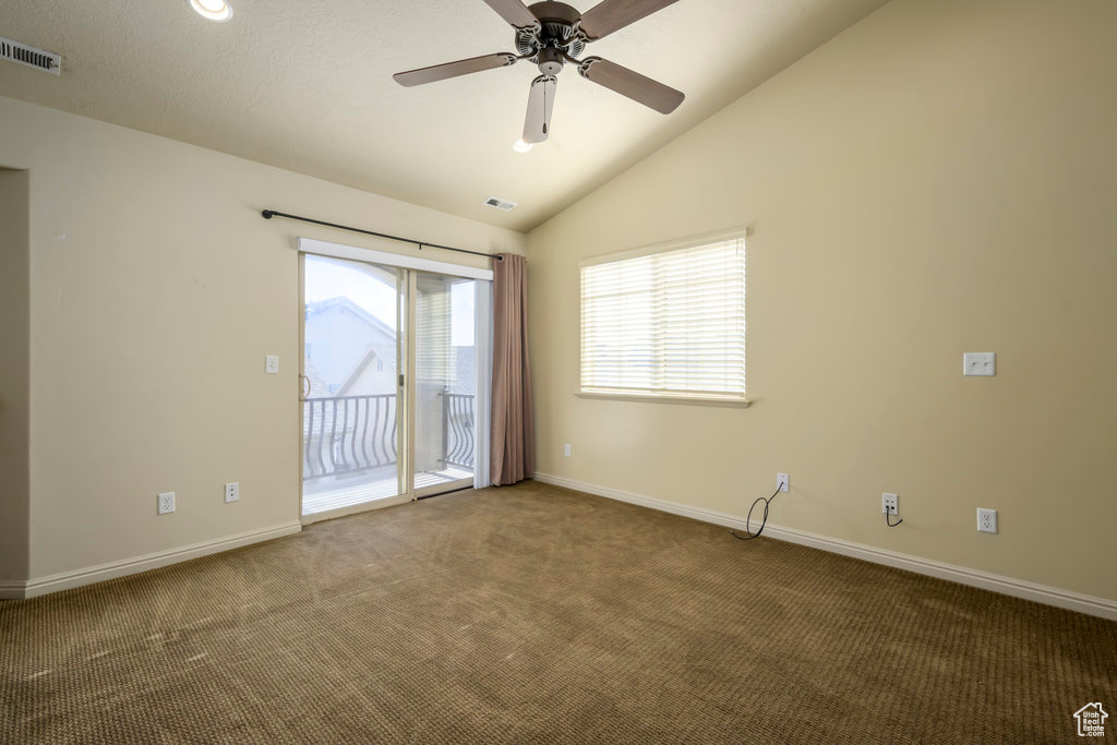 Carpeted empty room featuring vaulted ceiling, baseboards, a ceiling fan, and visible vents