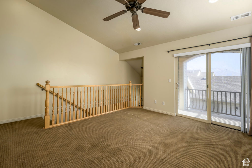 Carpeted spare room with vaulted ceiling, ceiling fan, baseboards, and visible vents