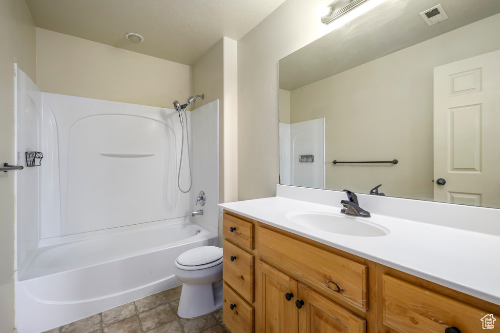 Bathroom with toilet, shower / tub combination, stone finish floor, visible vents, and vanity