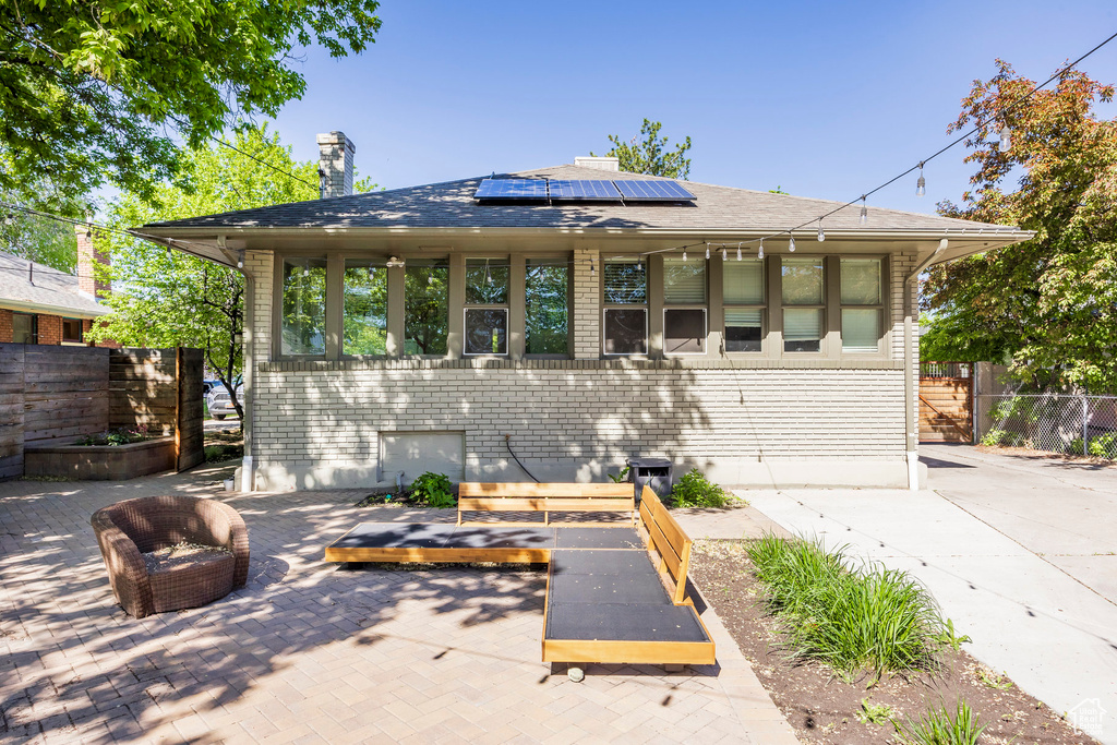 View of front of house featuring fence, a chimney, and solar panels