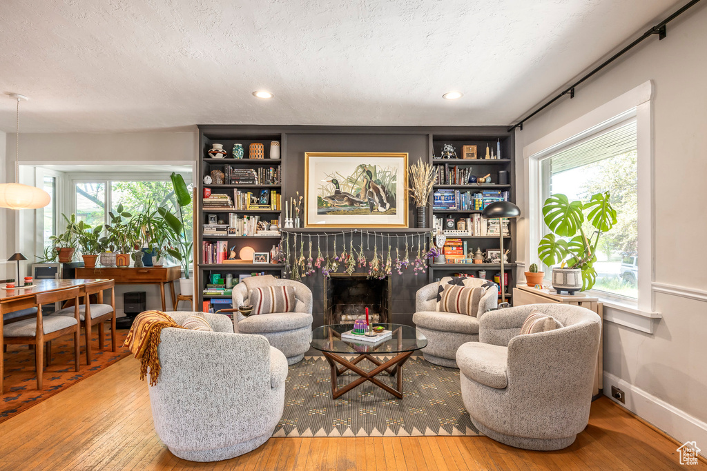 Sitting room featuring a fireplace, a textured ceiling, wood-type flooring, and a wealth of natural light