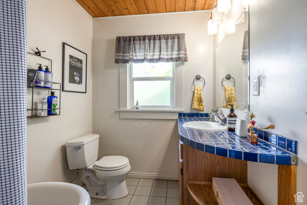 Bathroom with toilet, tile patterned floors, baseboards, wooden ceiling, and vanity