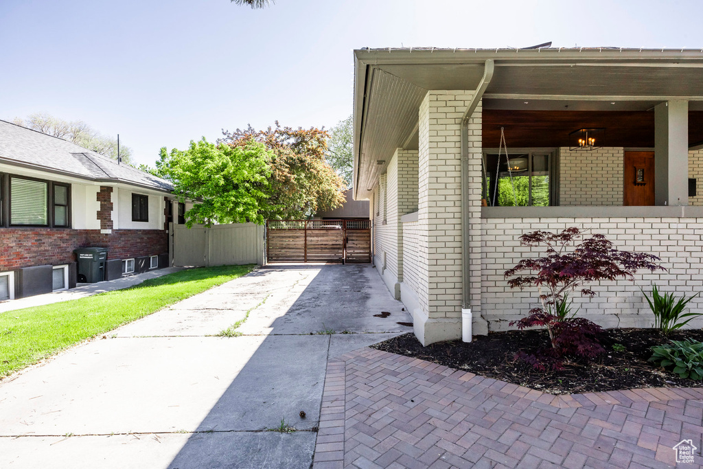 View of property exterior with brick siding, driveway, and a gate