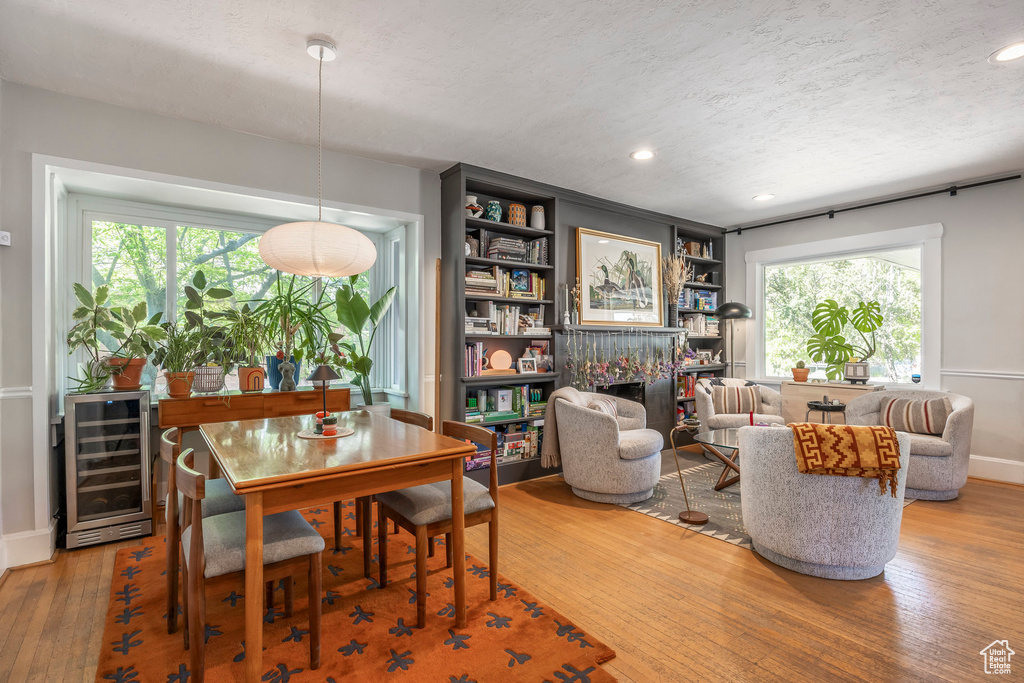 Interior space featuring beverage cooler, a textured ceiling, baseboards, and hardwood / wood-style flooring