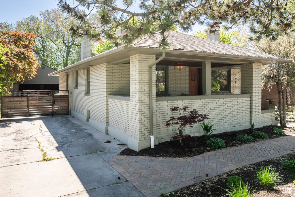 View of home's exterior featuring a chimney, roof with shingles, brick siding, and fence