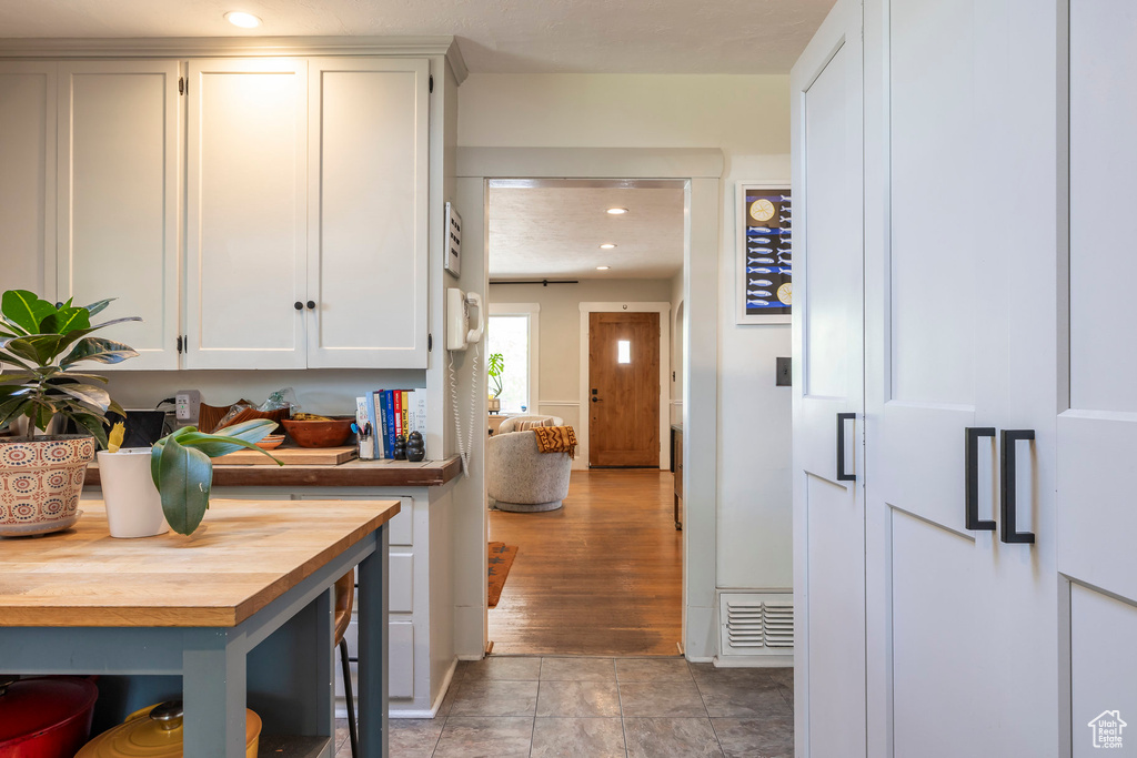 Kitchen with wood counters, white cabinets, and recessed lighting