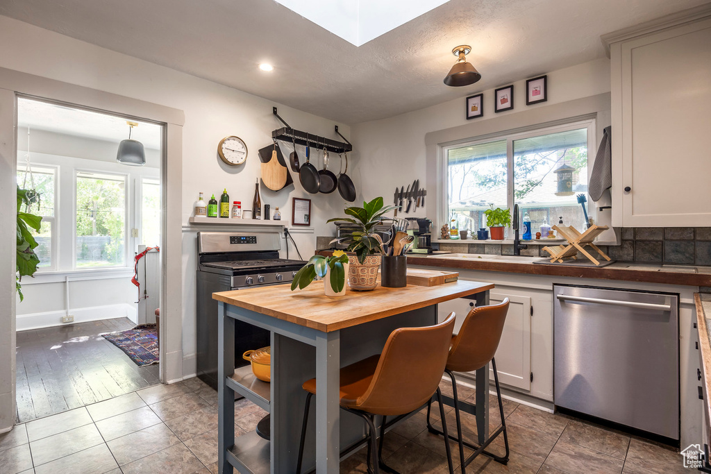 Kitchen with white cabinets, wooden counters, a wealth of natural light, and appliances with stainless steel finishes