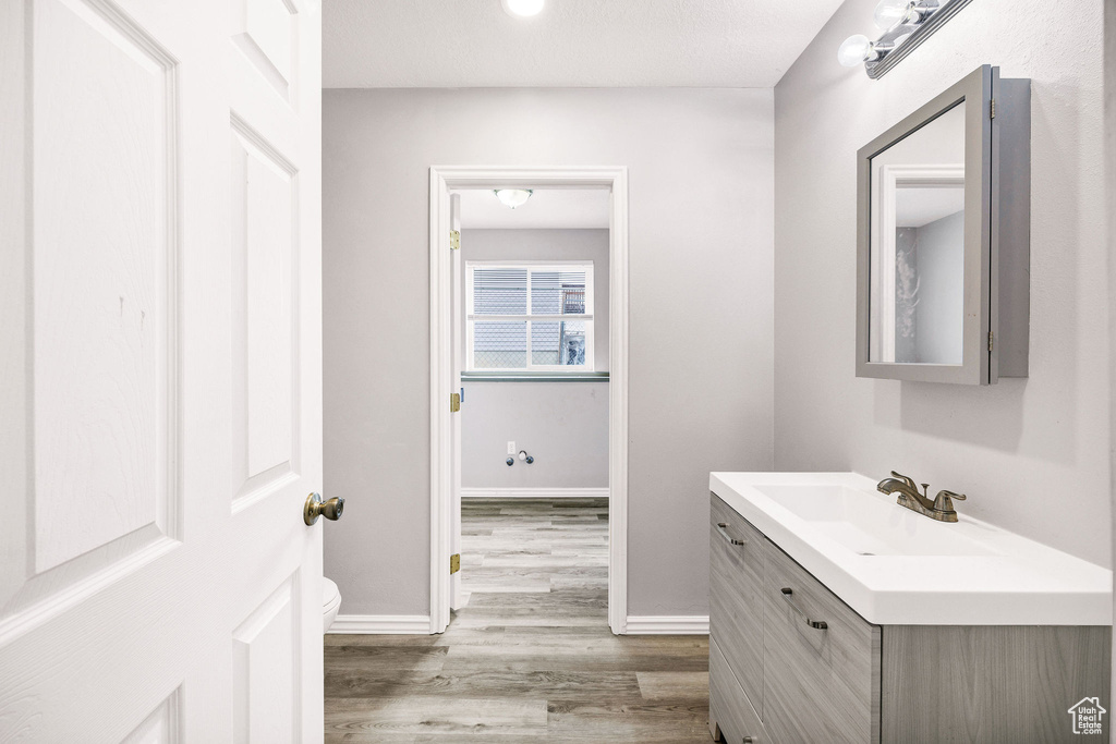 Bathroom featuring wood finished floors, vanity, toilet, and baseboards
