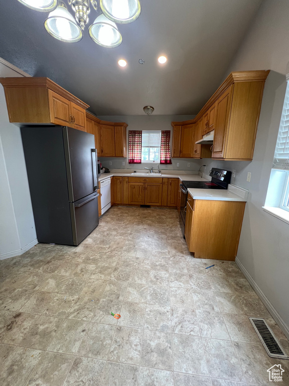 Kitchen with freestanding refrigerator, under cabinet range hood, visible vents, a sink, and light countertops