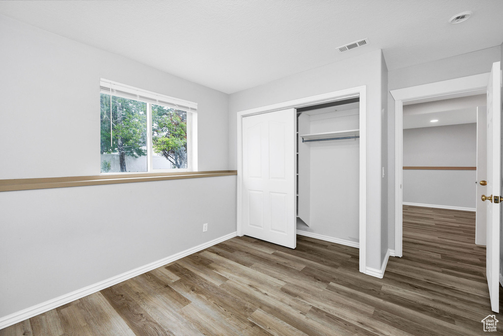 Unfurnished bedroom featuring wood finished floors, baseboards, a closet, and recessed lighting