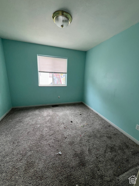 Spare room featuring carpet flooring and baseboards