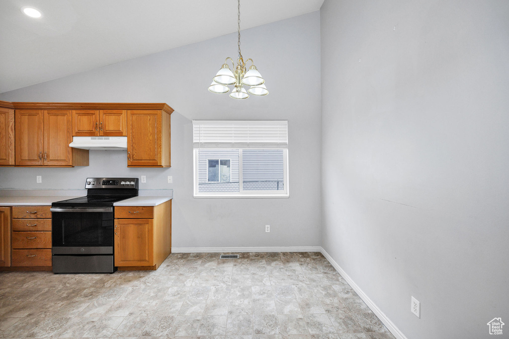 Kitchen with stainless steel electric range oven, under cabinet range hood, a chandelier, brown cabinets, and high vaulted ceiling