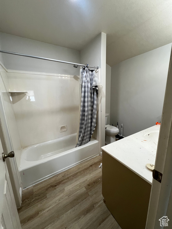 Bathroom with vanity, shower / bath combo, toilet, and wood finished floors
