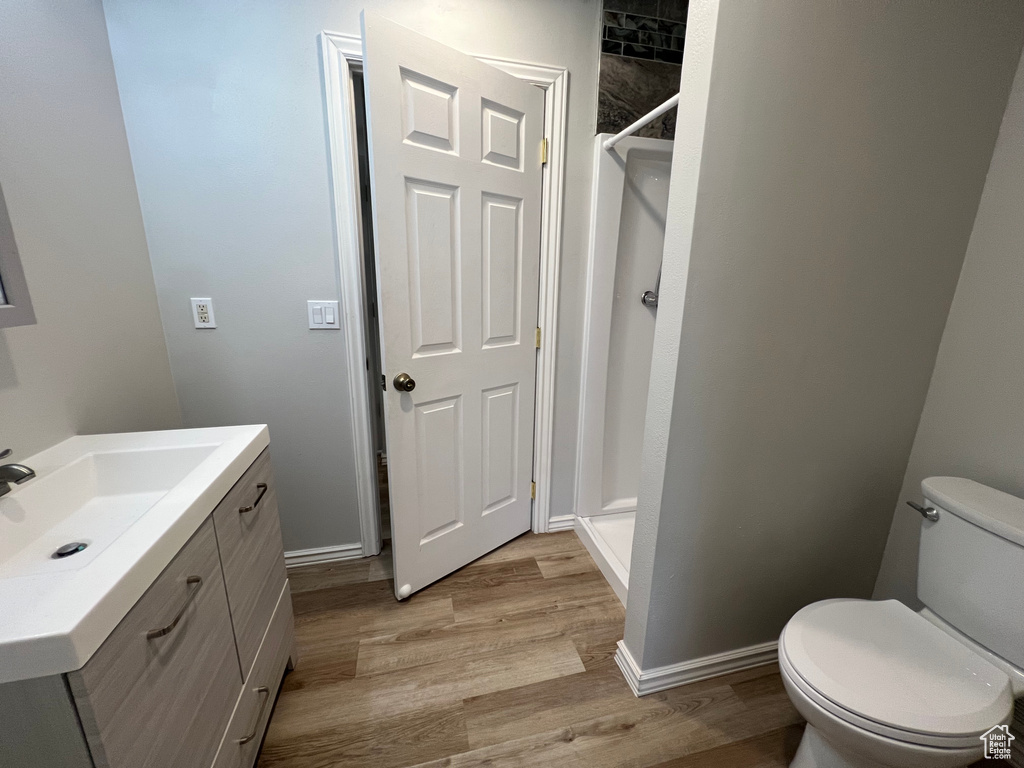 Bathroom featuring vanity, toilet, a shower stall, and wood finished floors