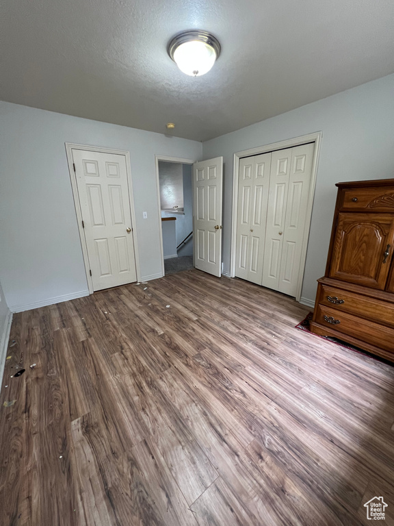 Unfurnished bedroom featuring a closet, wood finished floors, and baseboards