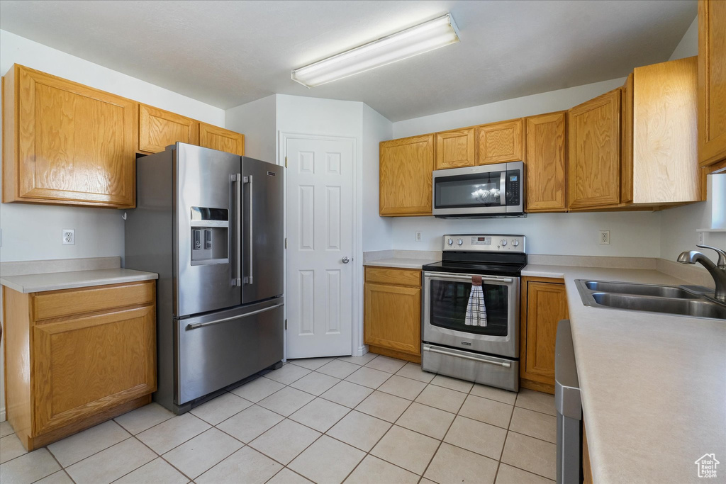 Kitchen with light countertops, stainless steel appliances, light tile patterned floors, and a sink