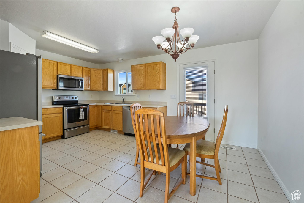 Kitchen with light countertops, a sink, a chandelier, stainless steel appliances, and light tile patterned flooring