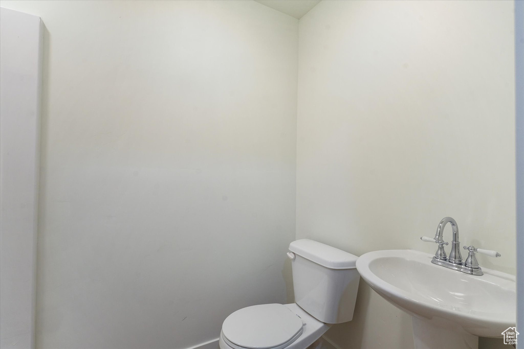 Half bath with toilet, baseboards, and a sink