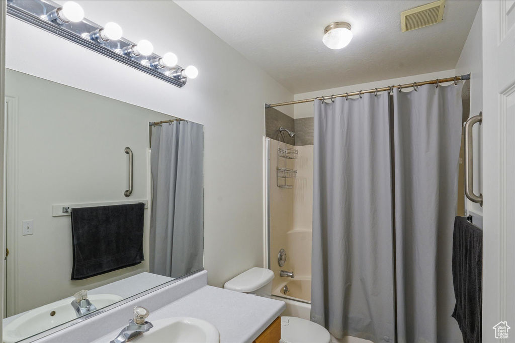Full bathroom featuring visible vents, shower / bath combination with curtain, toilet, and vanity