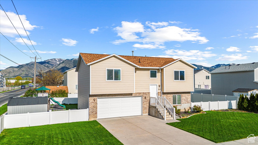 Split foyer home with a garage, fence, a mountain view, and brick siding