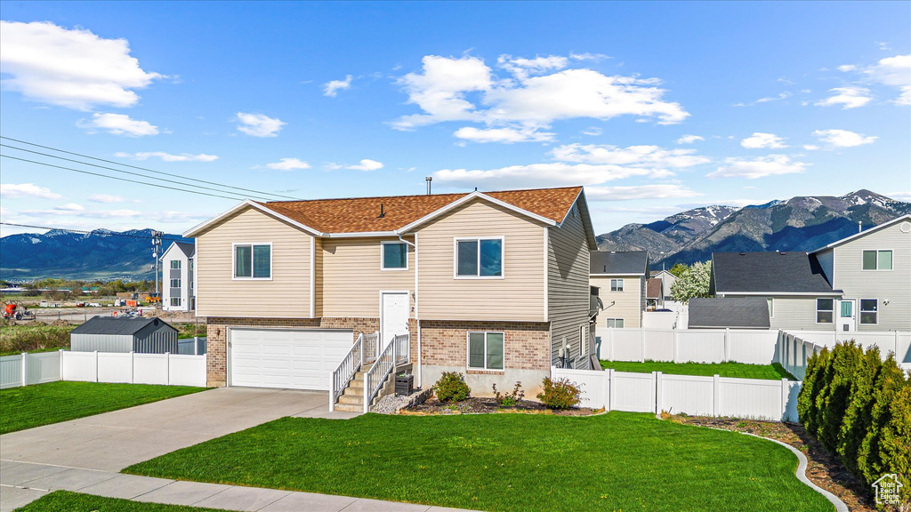 Bi-level home with a mountain view, driveway, a front lawn, and brick siding
