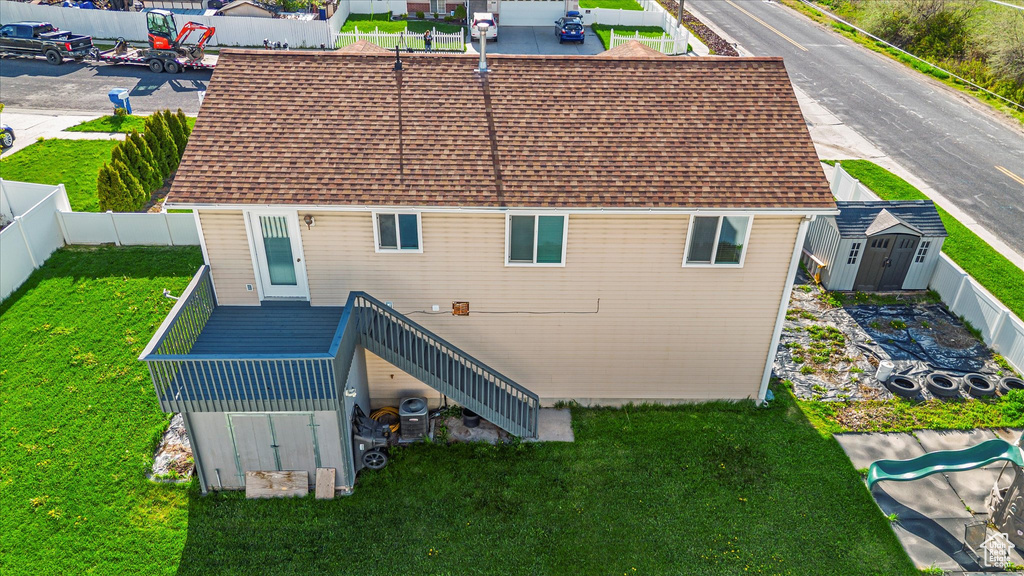 Rear view of house with an outbuilding, stairway, a fenced backyard, a storage unit, and a yard
