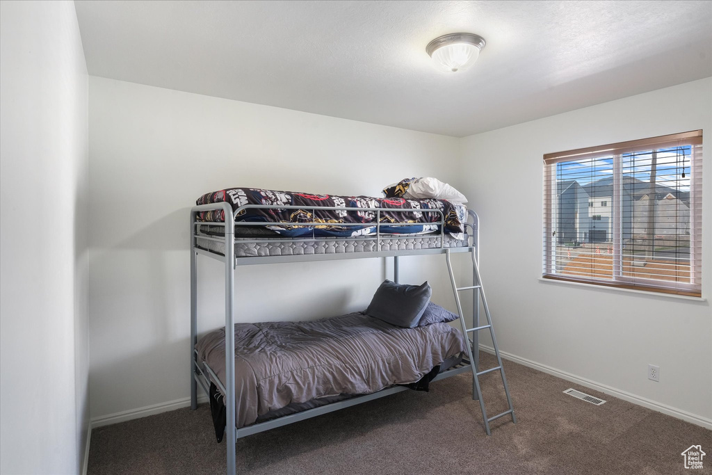 Carpeted bedroom with baseboards and visible vents
