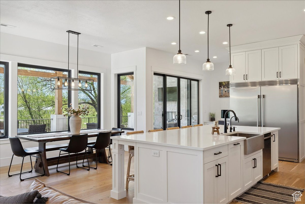 Kitchen featuring a sink, light wood-style floors, white cabinetry, light countertops, and appliances with stainless steel finishes