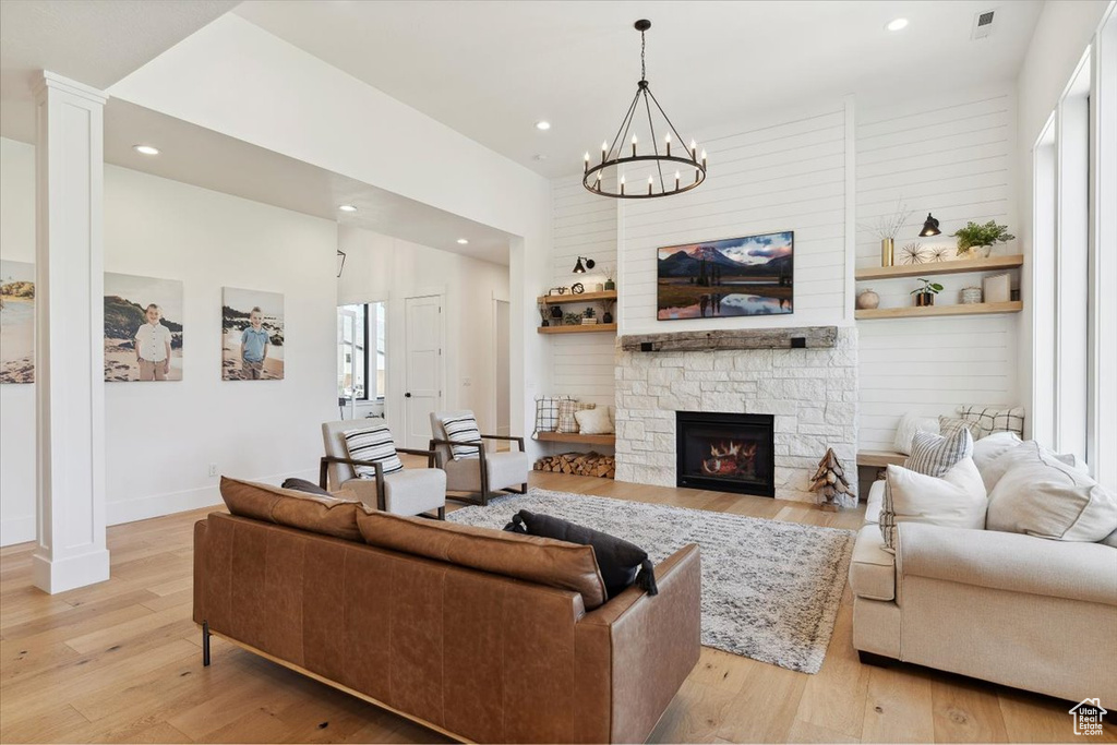 Living room with visible vents, recessed lighting, a fireplace, an inviting chandelier, and light wood-style floors