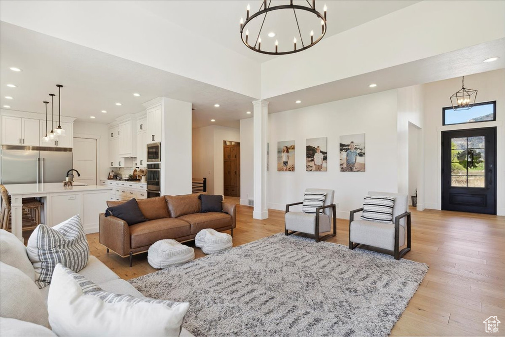 Living area with light wood-style floors, a chandelier, recessed lighting, and decorative columns