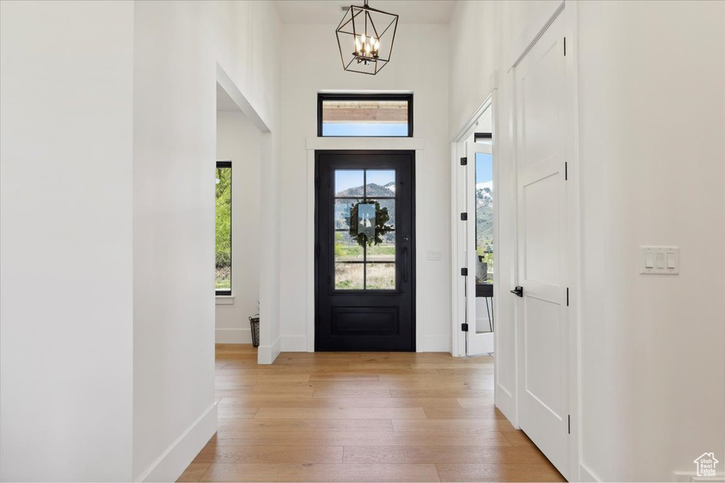 Foyer with a chandelier, light wood-style flooring, baseboards, and a towering ceiling