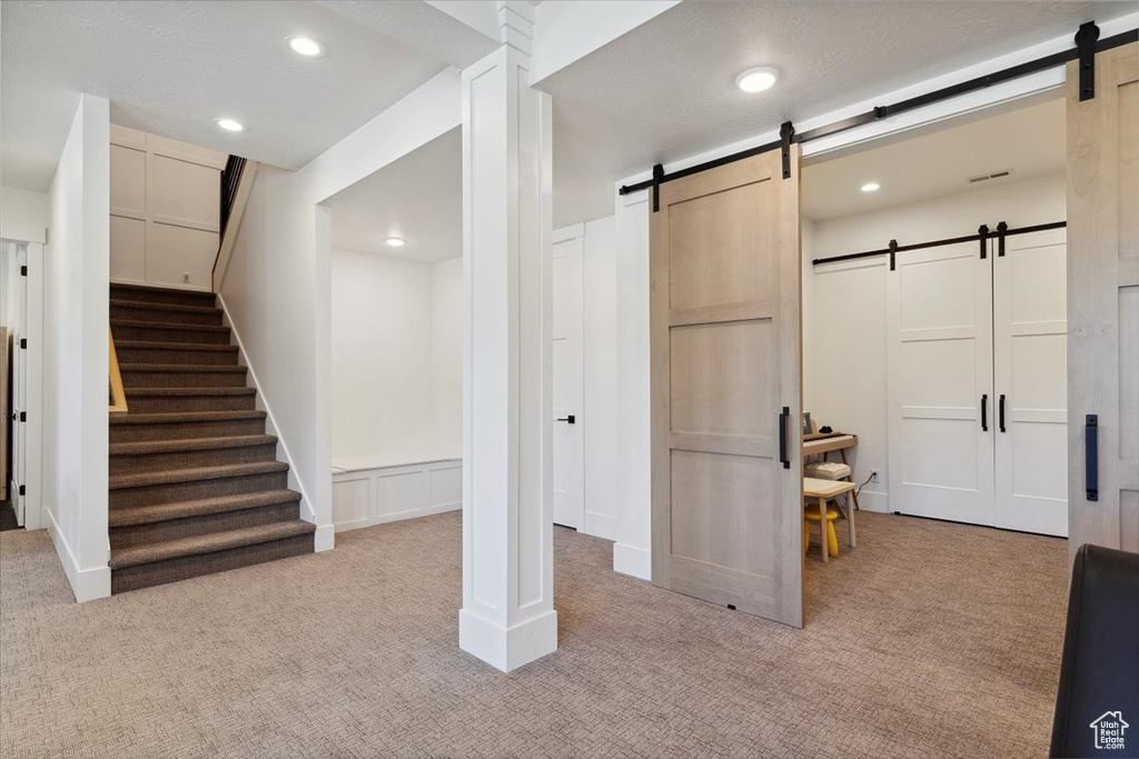 Below grade area featuring light carpet, a barn door, and recessed lighting