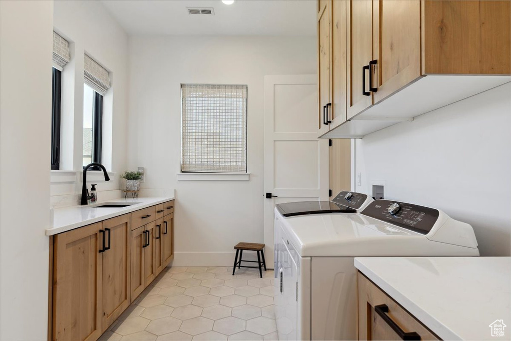 Clothes washing area featuring a sink, cabinet space, independent washer and dryer, visible vents, and light tile patterned floors