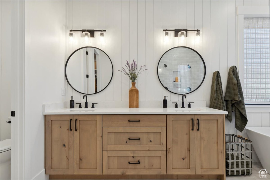 Full bath featuring double vanity, a freestanding bath, toilet, and a sink