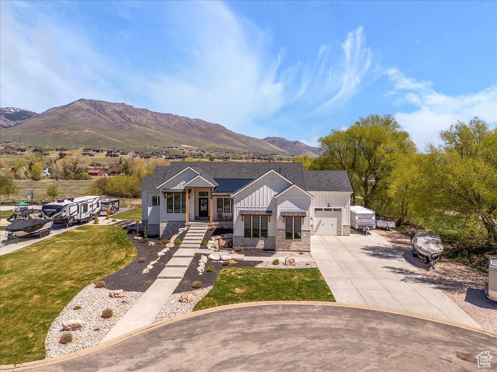 View of front of property featuring board and batten siding, driveway, a mountain view, an attached garage, and stone siding