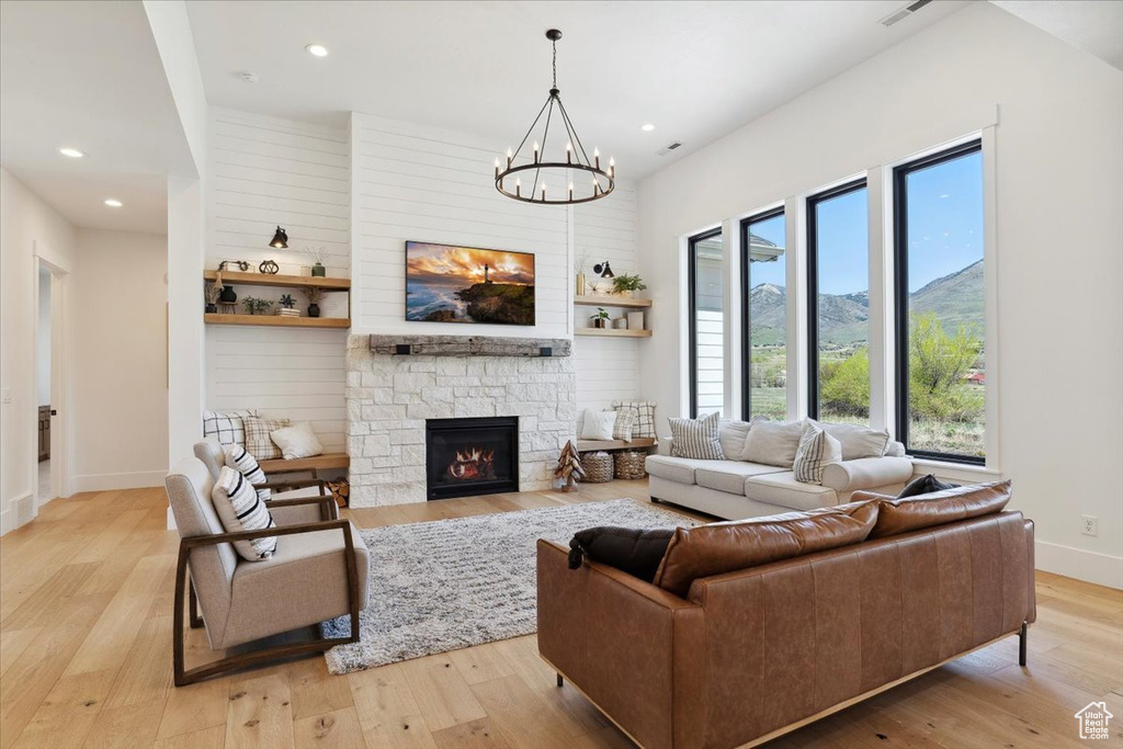 Living room with recessed lighting, a fireplace, a chandelier, light wood-style flooring, and baseboards