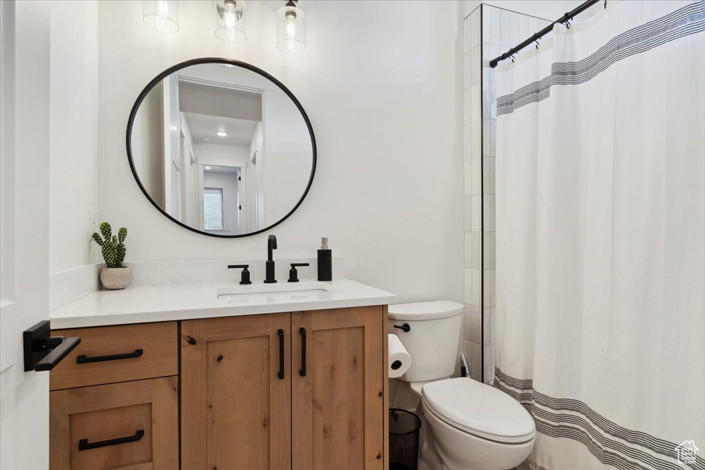 Full bath with toilet, curtained shower, and vanity
